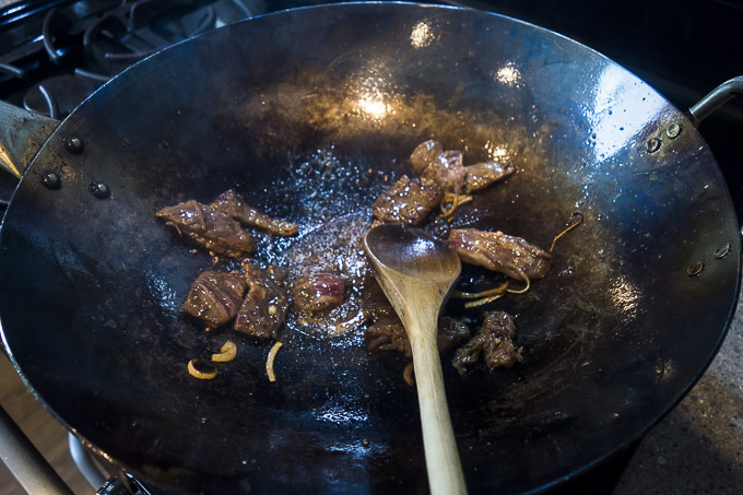 beef being seared in a wok 