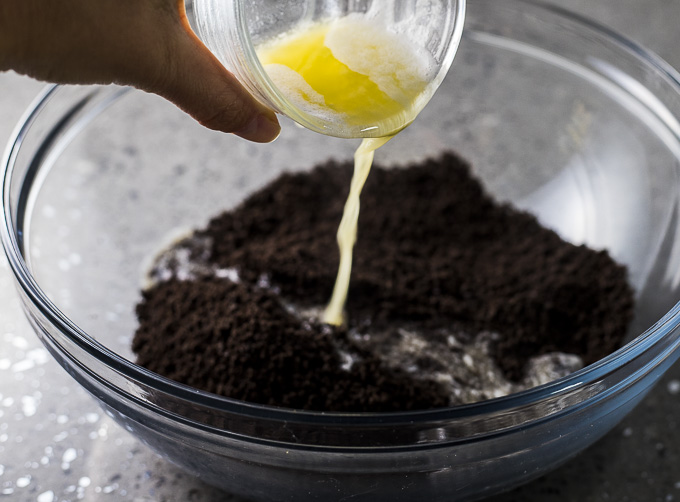 melted butter poured in a bowl of crushed oreos