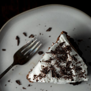 a piece of chocolate pie with whipped cream and shaved chocolate on a plate