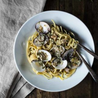 bowl of linguini with white clam sauce with fork and spoon