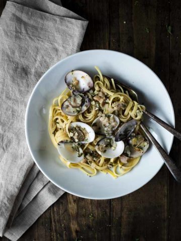 bowl of linguini with white clam sauce with fork and spoon