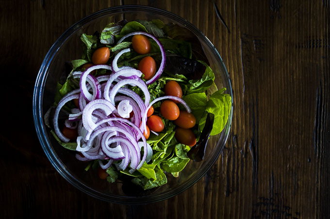 greens, tomatoes and red onions in a bowl