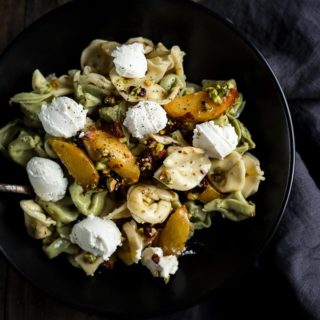 tortellini with peaches and ricotta cheese dollops in a bowl