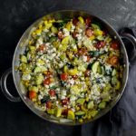 sauteed squash and vegetables sprinkled with cheese in a skillet