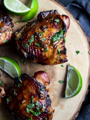 roasted chicken thighs garnished with cilantro and fresh limes