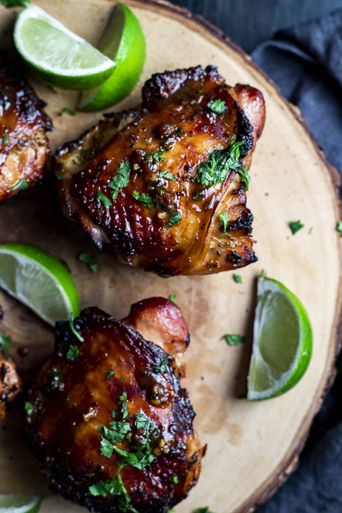 roasted chicken thighs garnished with cilantro and fresh limes