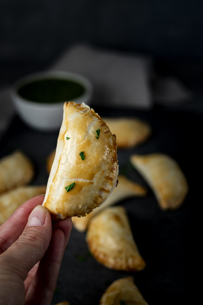 a hand holding an empanada