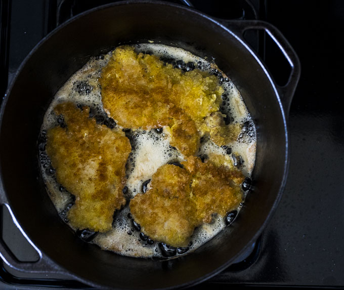 chicken cutlets frying in a dutch oven