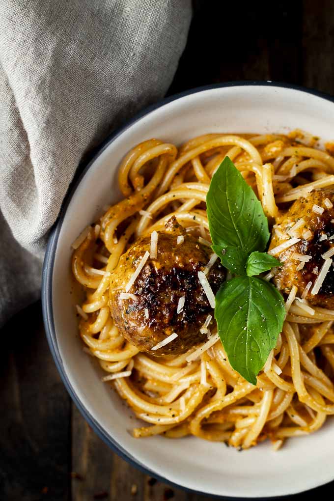 meatballs and pasta in creamy red pepper pesto sauce in a bowl