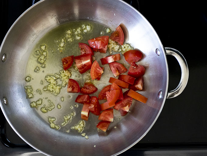 tomatoes and garlic with olive oil in a skillet