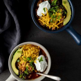 2 bowls of chili with cheese, sour cream and avocado