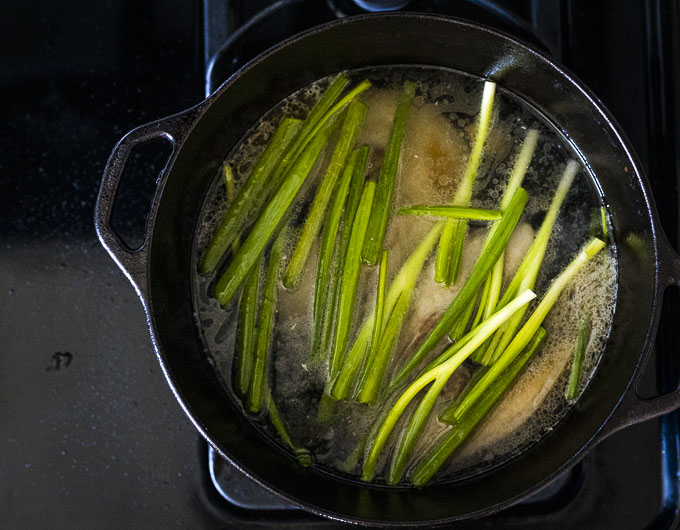 pork and green onions in a broth in a dutch oven