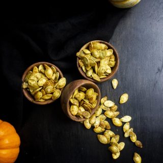 bowls of roasted pumpkin seeds with one spilled