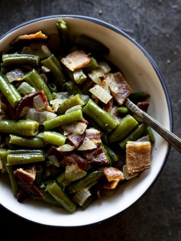green beans mixed with bacon and onions in a bowl