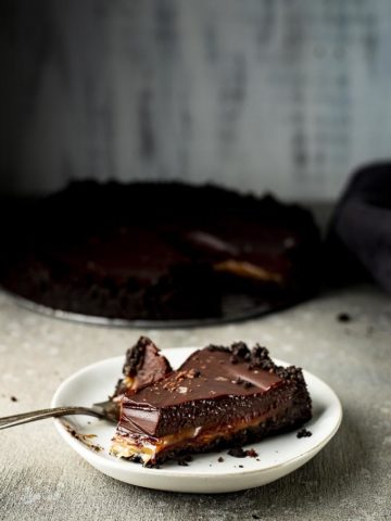 piece of chocolate tart with full pie in the background