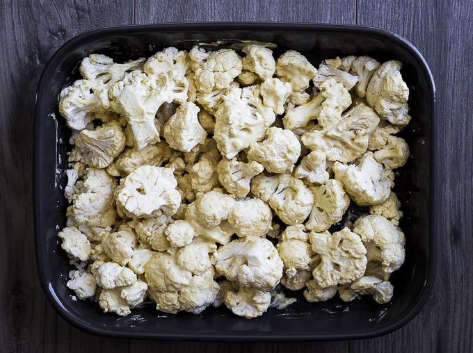 raw cauliflower covered in white sauce in a baking dish