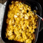 cheesy cauliflower in a baking dish with a serving spoon