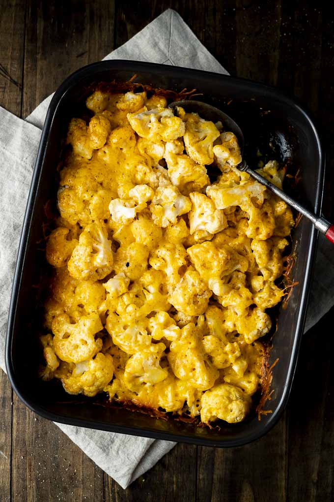 cheesy cauliflower in a baking dish with a serving spoon