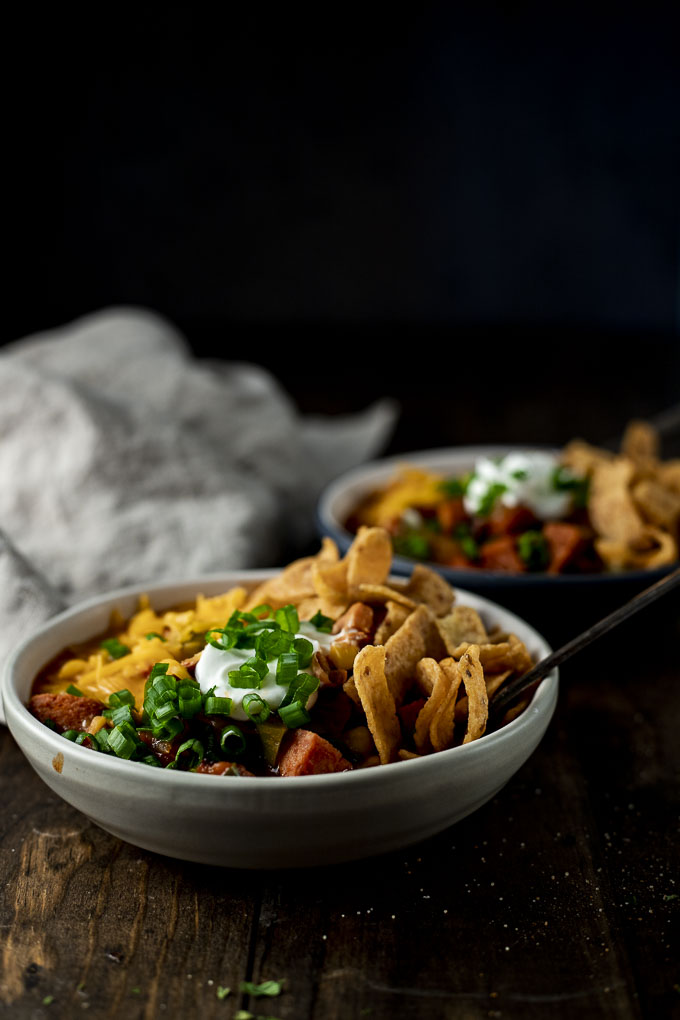 2 bowls of chili with fritos garnished with green onions