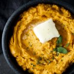 bowl of mashed sweet potatoes with butter and fresh sage