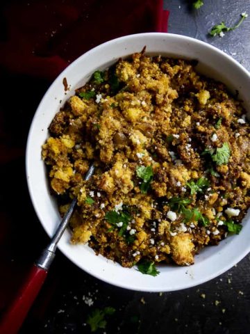cornbread stuffing in a round baking dish with a spoon