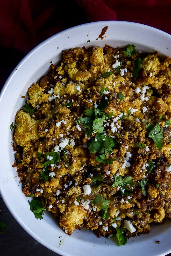 cornbread stuffing garnished with cheese and cilantro in a baking dish