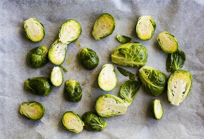 brussels sprouts coated with olive oil on parchment paper