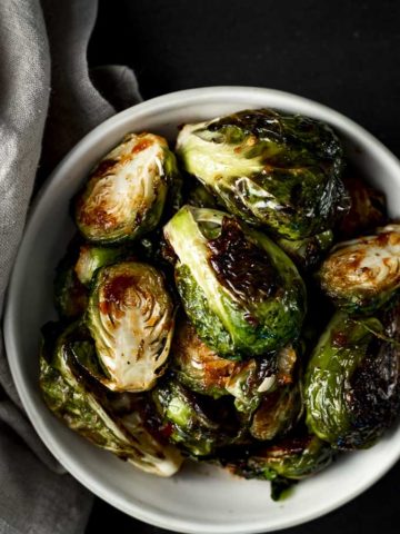bowls of spicy roasted brussels sprouts with charred edges