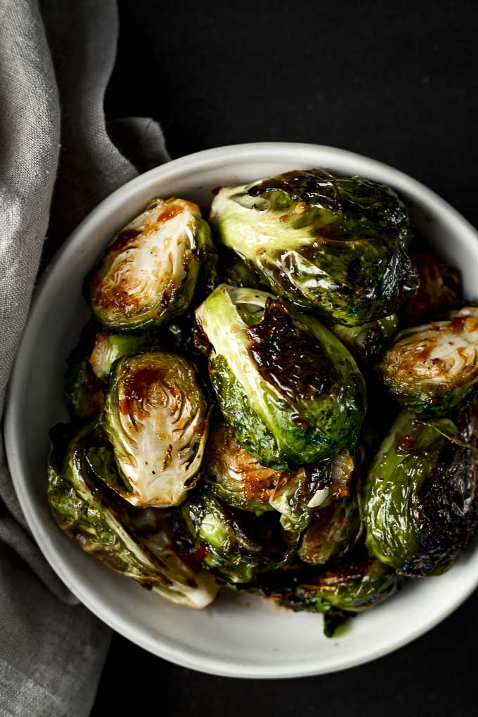 bowls of spicy roasted brussels sprouts with charred edges