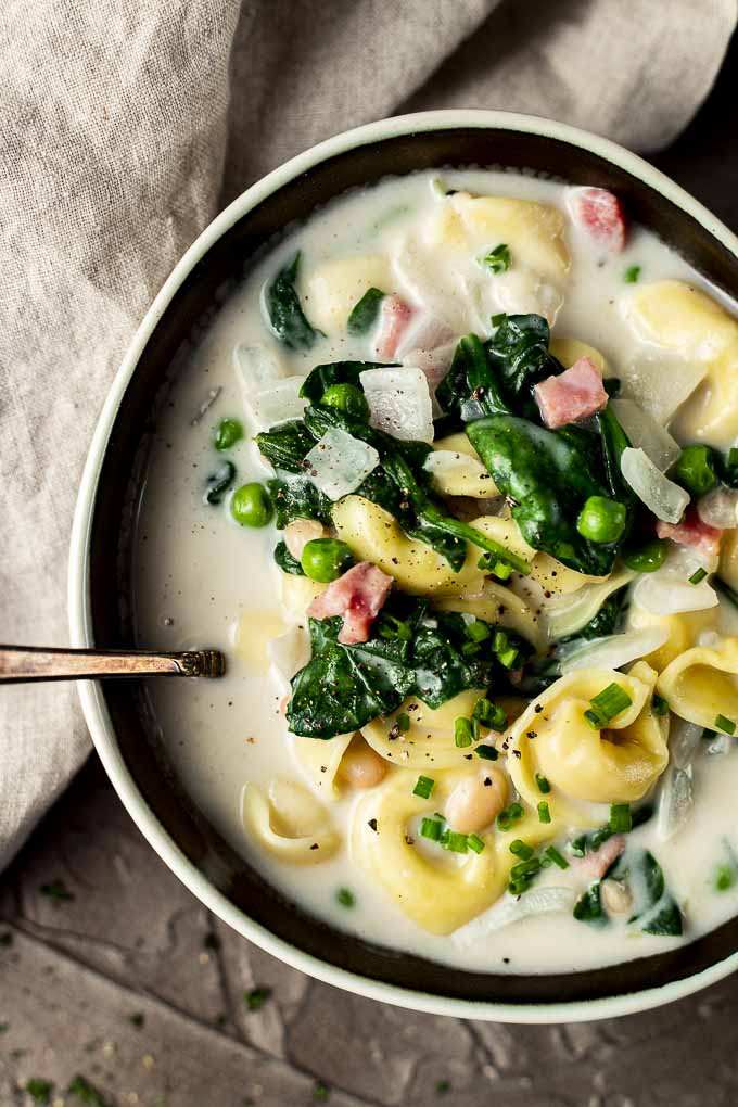 bowl of tortellini soup with spinach and peas