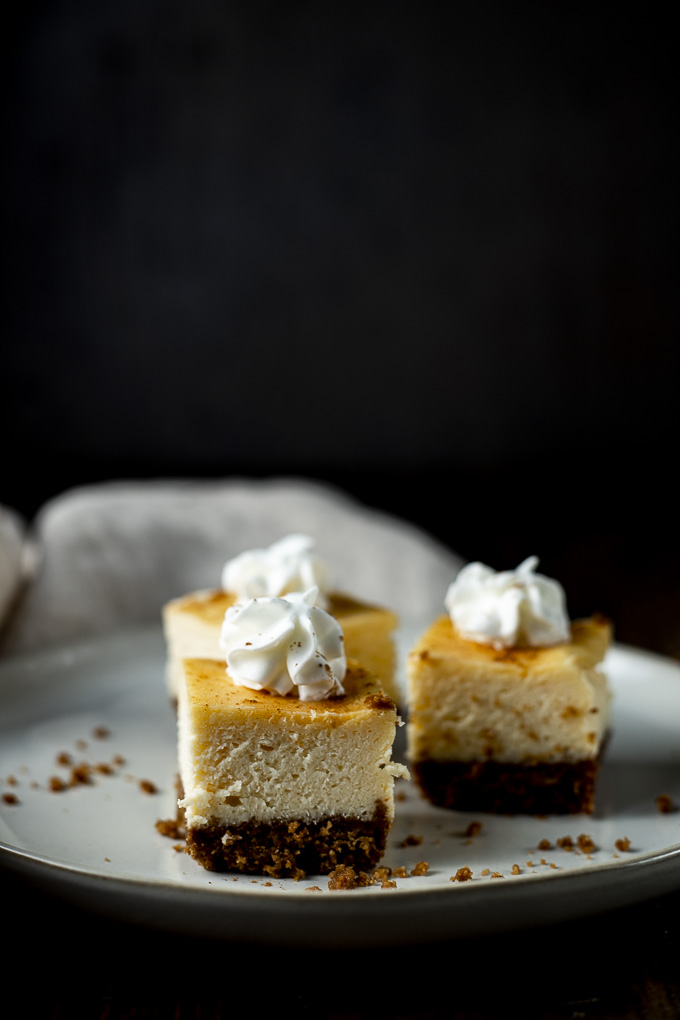 side view of eggnog cheesecake bars on a plate topped with whipped cream