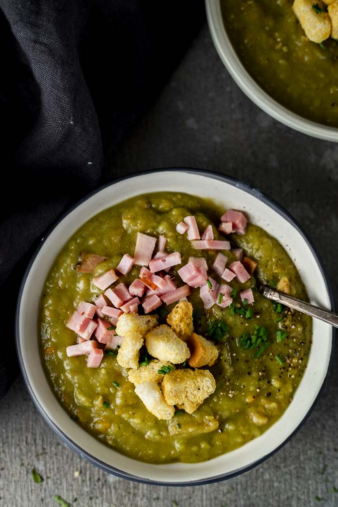 a bowl of split pea soup with hams and croutons