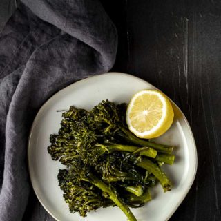 sauteed broccolini on a plate with a lemon