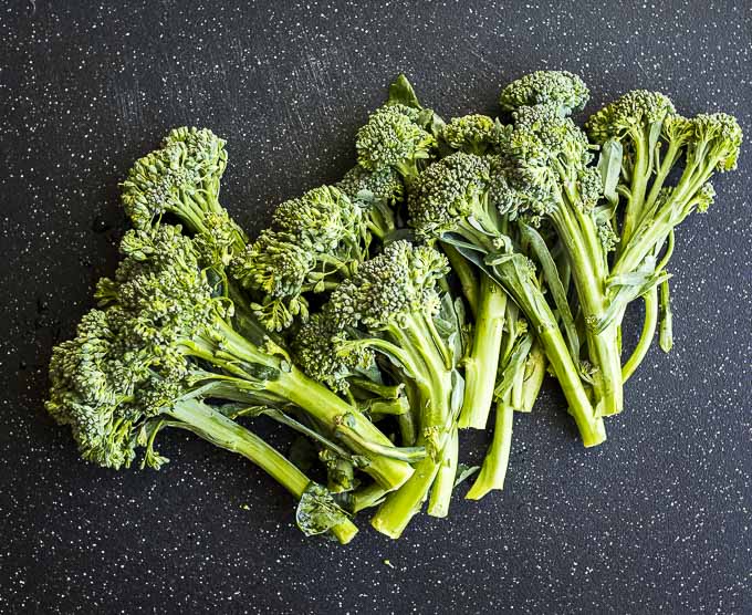 raw broccolini on a cutting board
