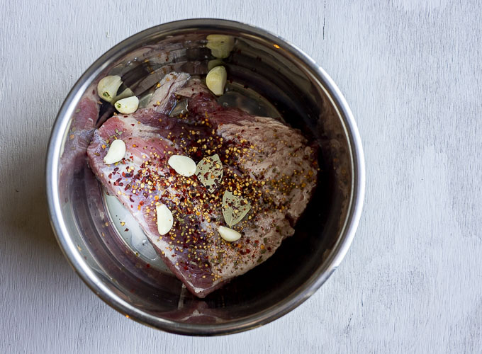 corned beef in a pot with garlic cloves and seasoning