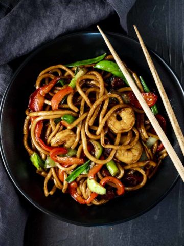 shrimp lo mein in a bowl with chopsticks