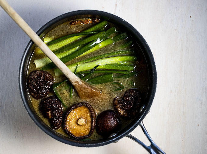 pot of broth with mushrooms, green onions and ginger