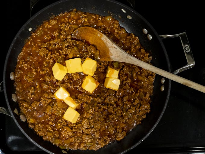 red gravy in a skillet with cubes of velveeta