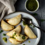 a plate of vegetarian empanadas drizzled with green chimichurri sauce