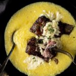 beef short ribs in a bowl of polenta with cream sauce