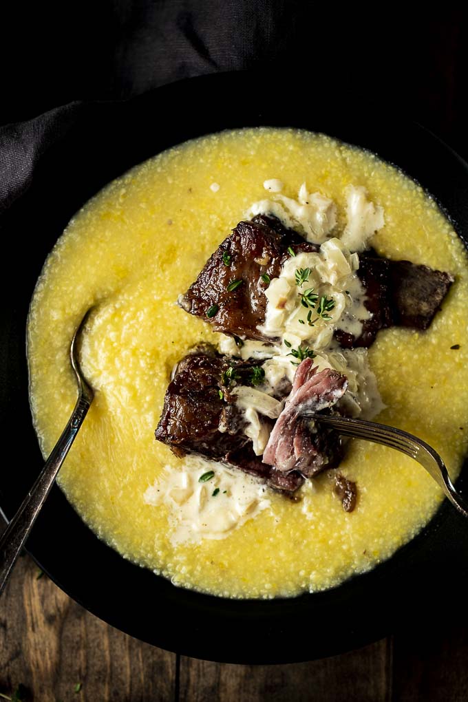 beef short ribs in a bowl of polenta with cream sauce