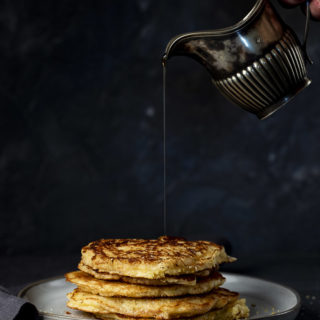 stack of cornmeal pancakes with syrup being poured on