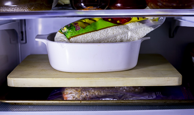 salmon in the fridge topped with a board and baking dish