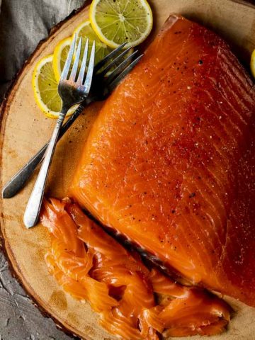 sliced cured salmon on a platter with lemon slices