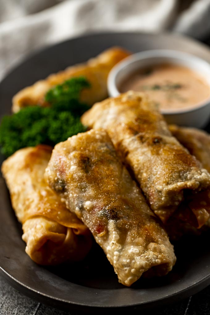 plate of fried egg rolls with orange sauce and pasrley