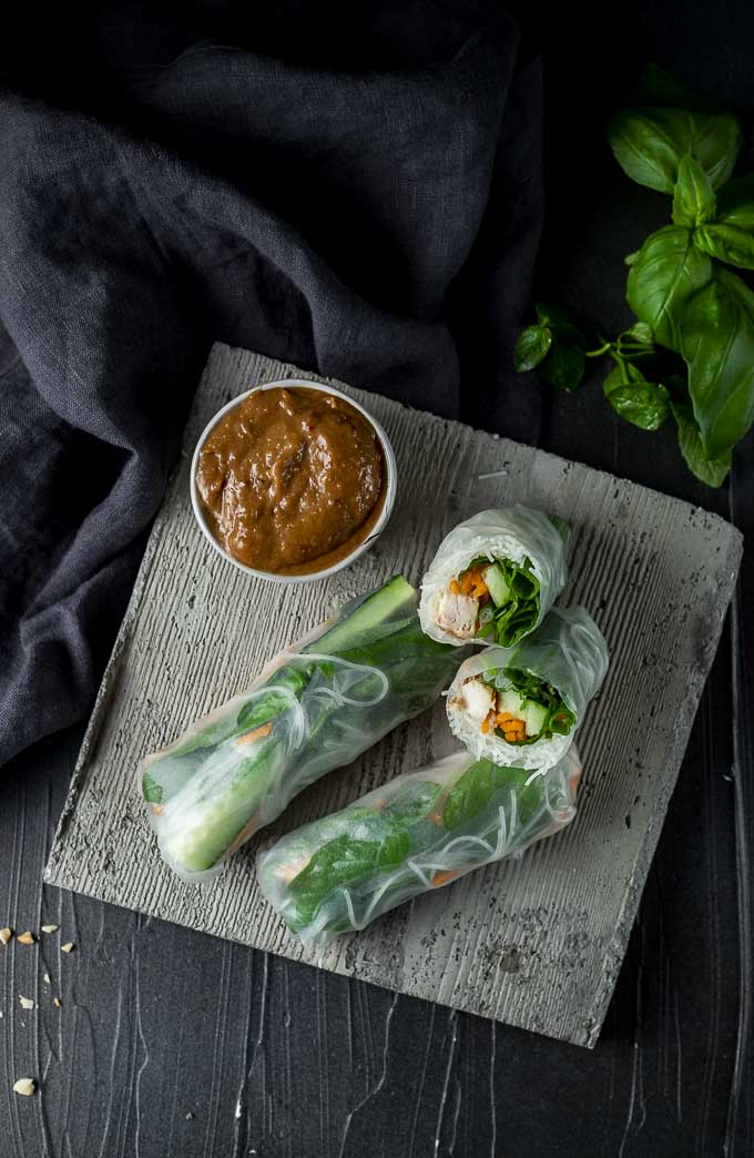 summer rolls with one halved on a plate with brown dipping sauce