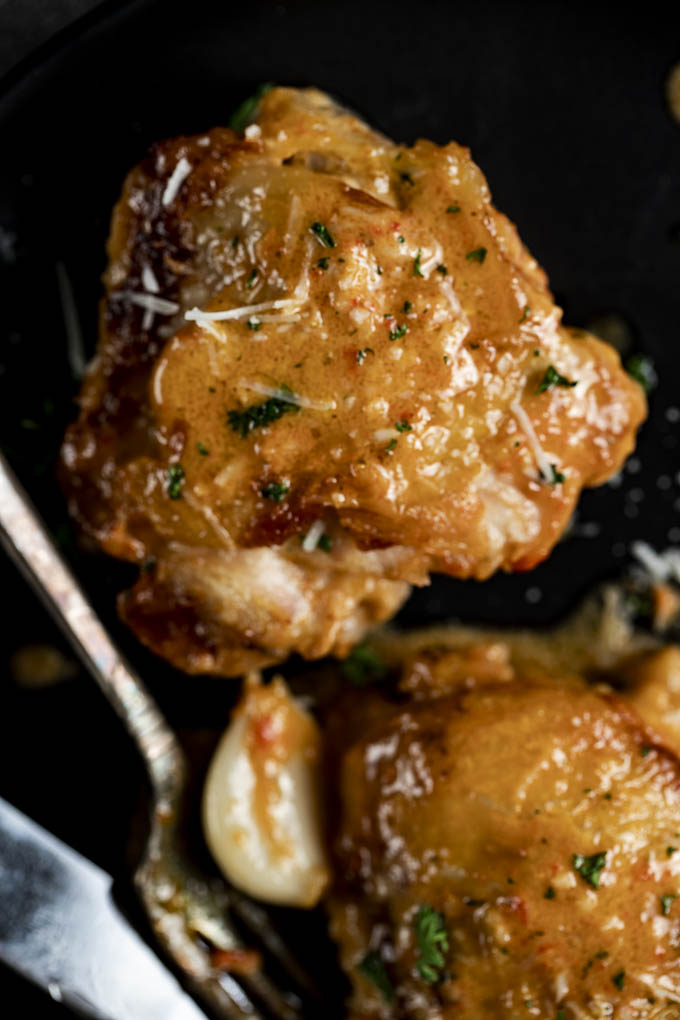 chicken thigh with creamy sauce on a plate sprinkled with cheese
