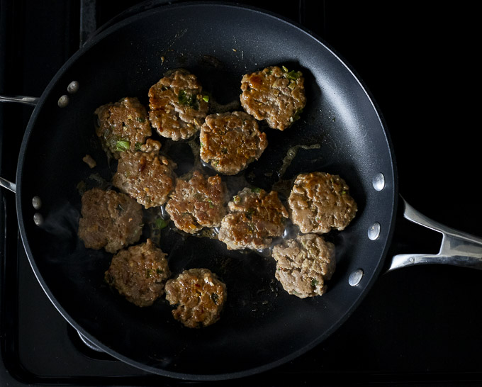 flattened meatballs fried in a pan
