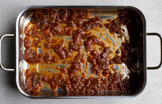 marinara sauce in the bottom of a lasagna pan