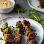 3 grilled beef skewers with peanut sauce and cilantro